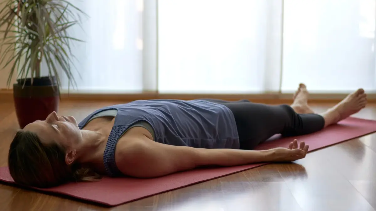 Kobieta leżąca na macie podczas praktyki jogi nidry