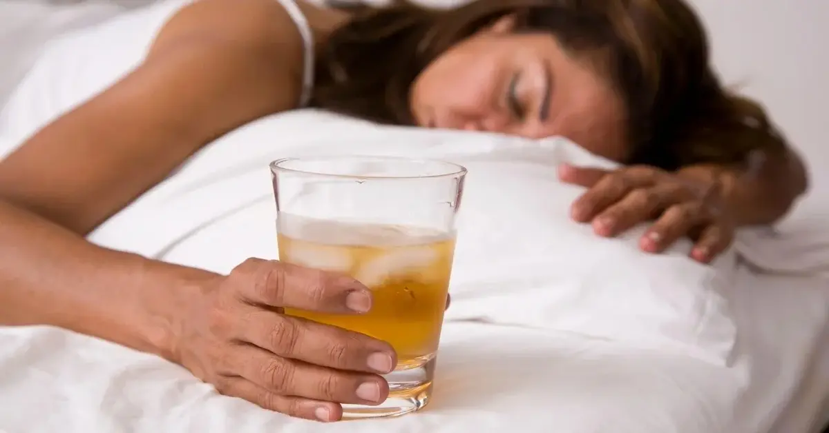 Kobieta śpiące ze szklanką alkoholu w ręce