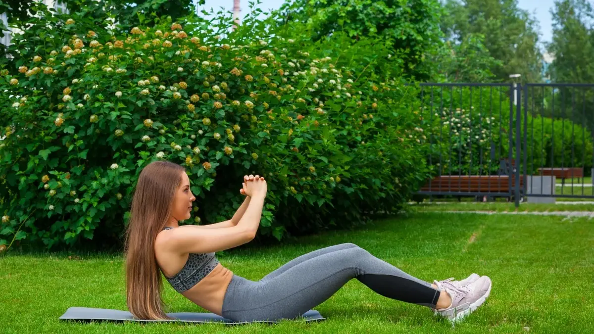 Kobieta w stroju sportowym ćwicząca w ogrodzie 