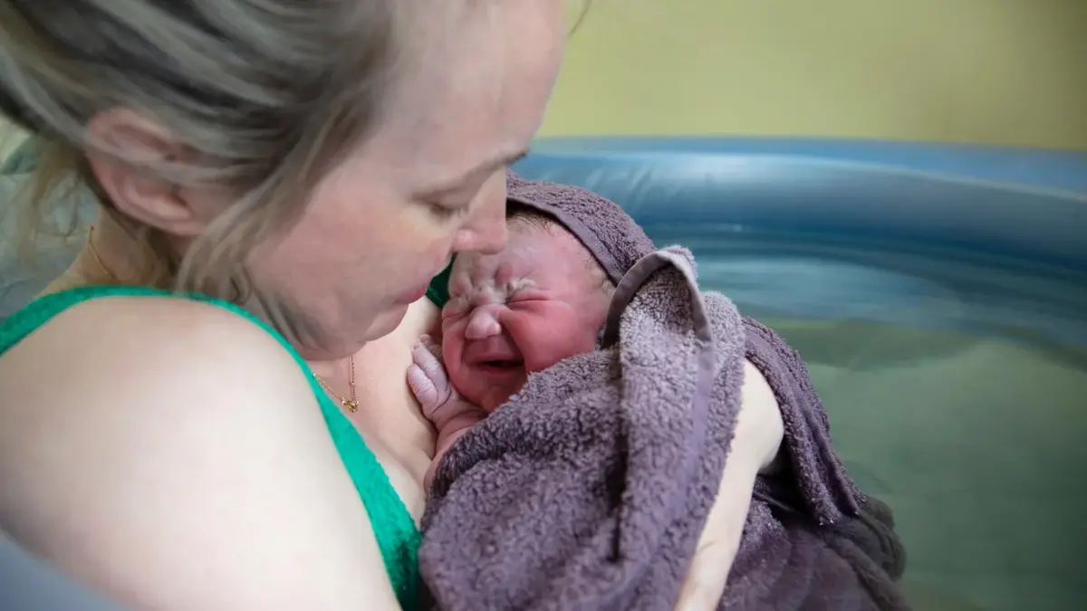 Kobieta trzymająca w ramionach noworodka 