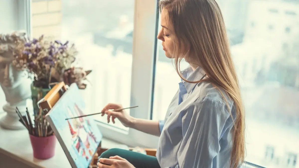 Kobieta malująca obrazek przy sztaludze 