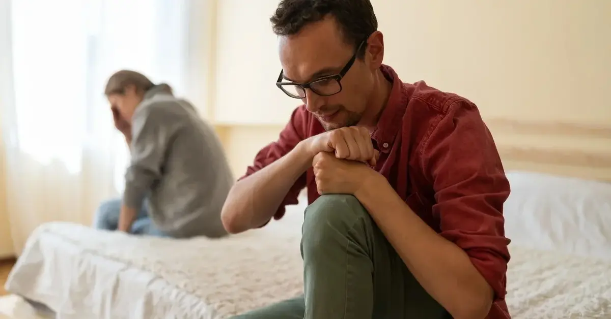 Para siedząca na łóżku odwrócona do siebie plecami