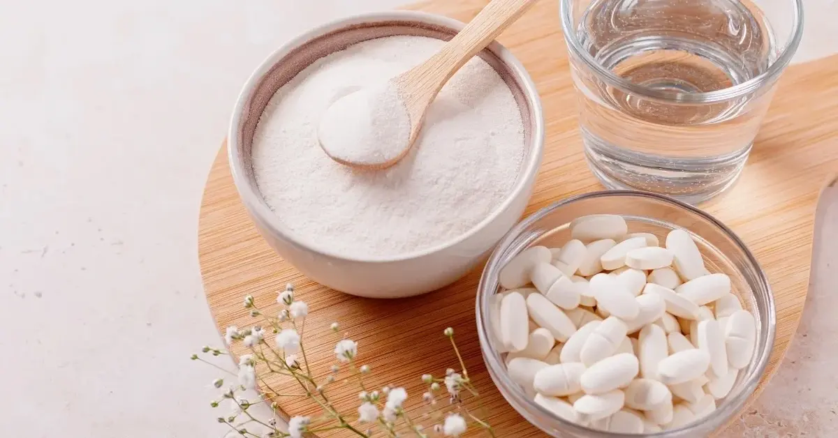 Kolagen w proszku, obok szklanka wody i pojemnik z kolagenem