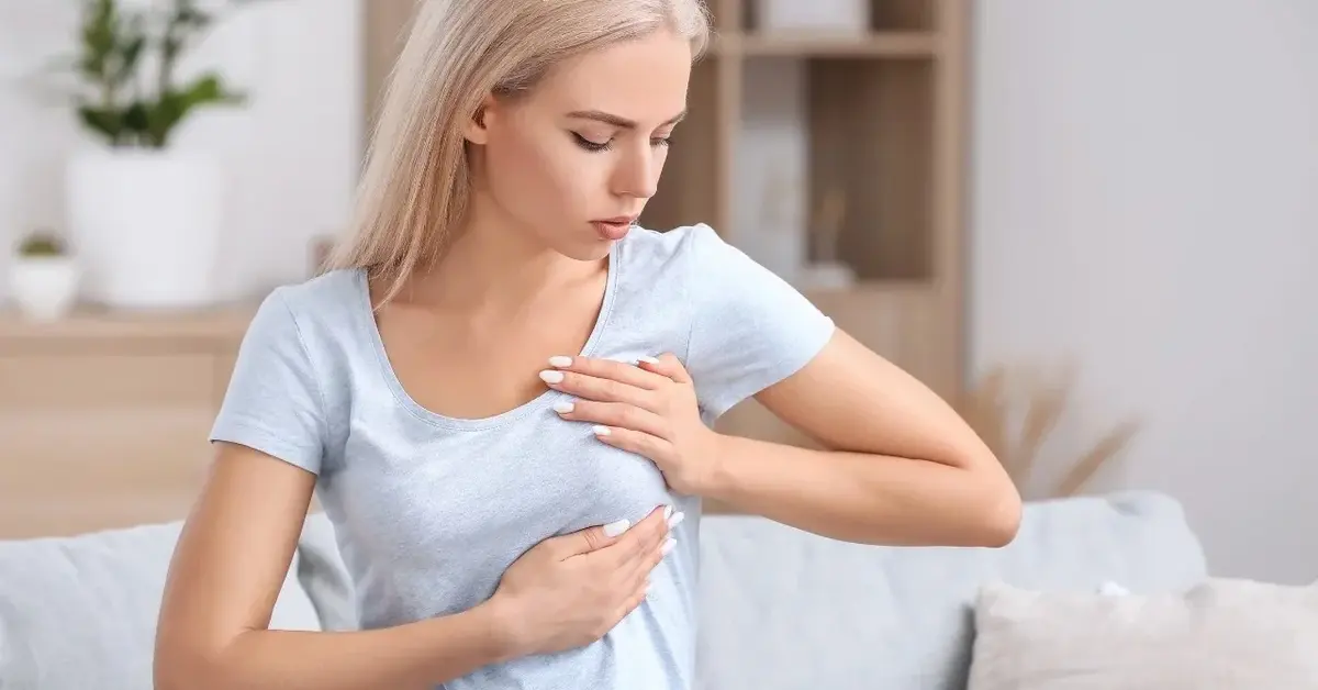 Kobieta w białej koszulce podczas samobadania piersi