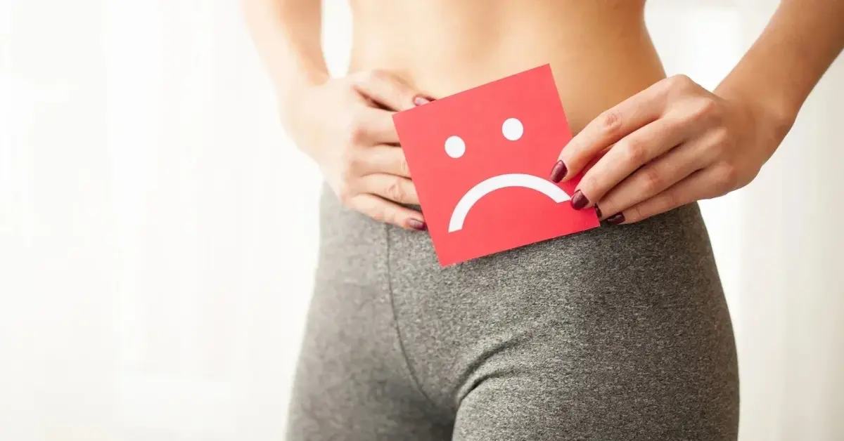 Kobieta trzymająca na wysokości pasa karteczkę ze smutną buzią