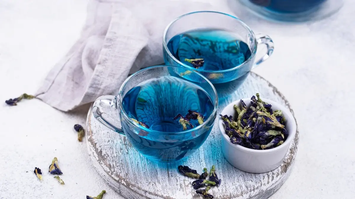 Niebieska herbata w szklanych filiżankach na białym tle 