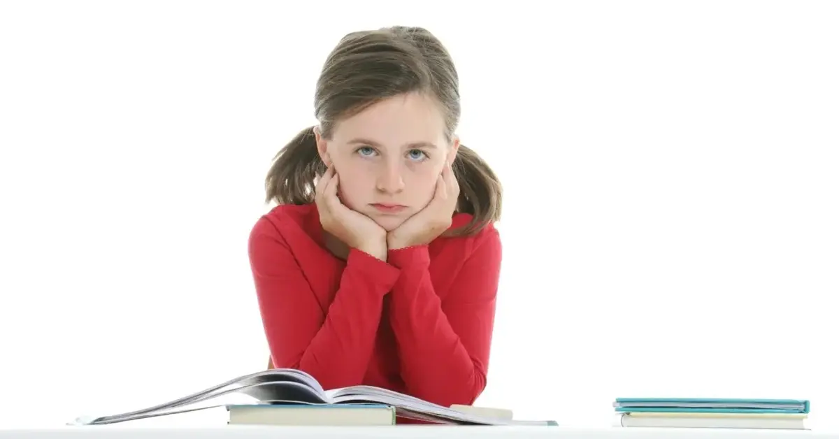 Dziewczynka przy biurku z książką z głową opartą na rękach