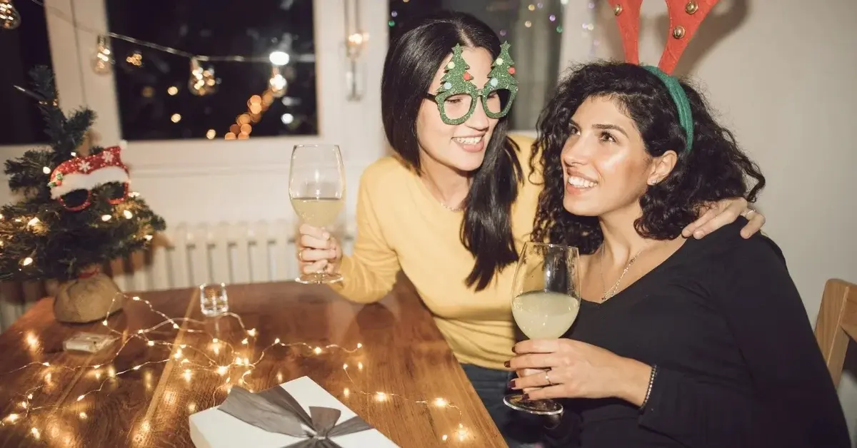 Dwie kobiety siedzące przy stole z kieliszkami szampana w rękach 