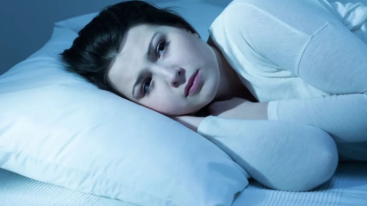 Kobieta leżąca w łóżku z głową opartą o poduszkę