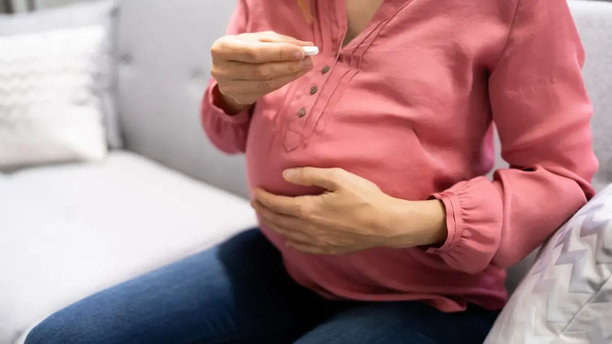 Kobieta w ciąży zażywająca kwas foliowy w tabletce