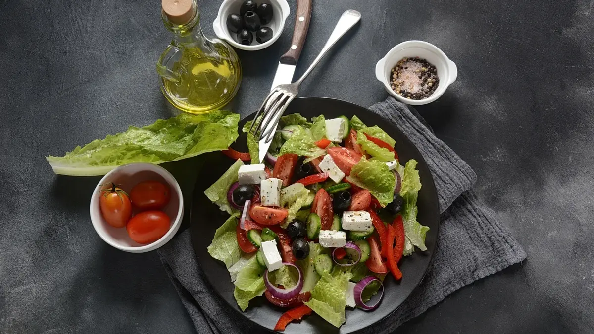 Salatka grecka na talerzu, obok składniki i dodatki do sałatki i sosu