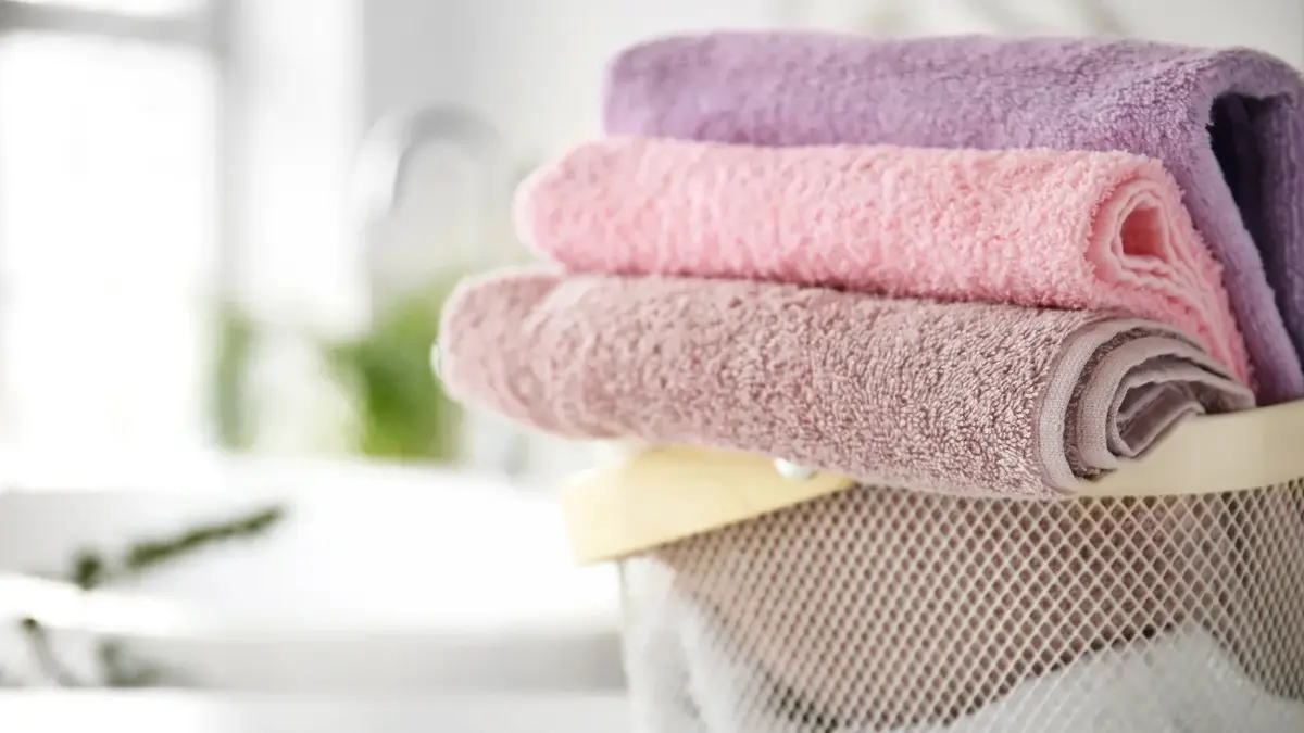Ręczniki złożone w kostke w metalowym koszu na pranie