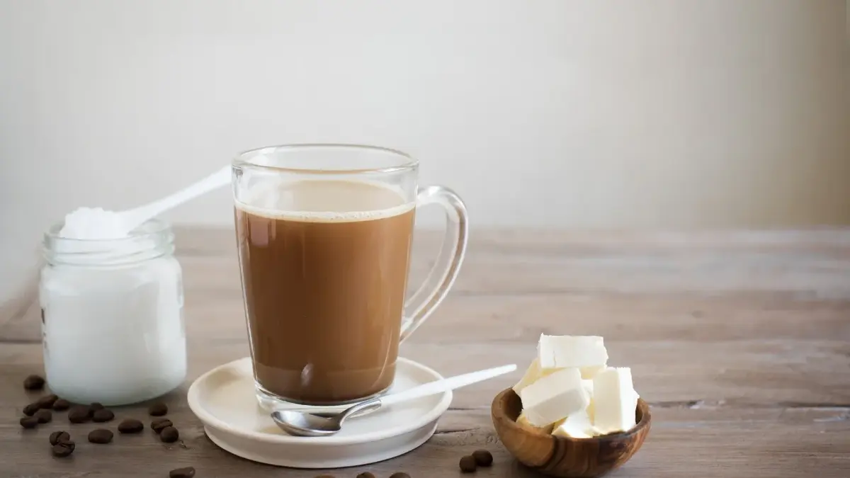 Kawa kuloodporna w szklance, obok masło i olej kokosowy