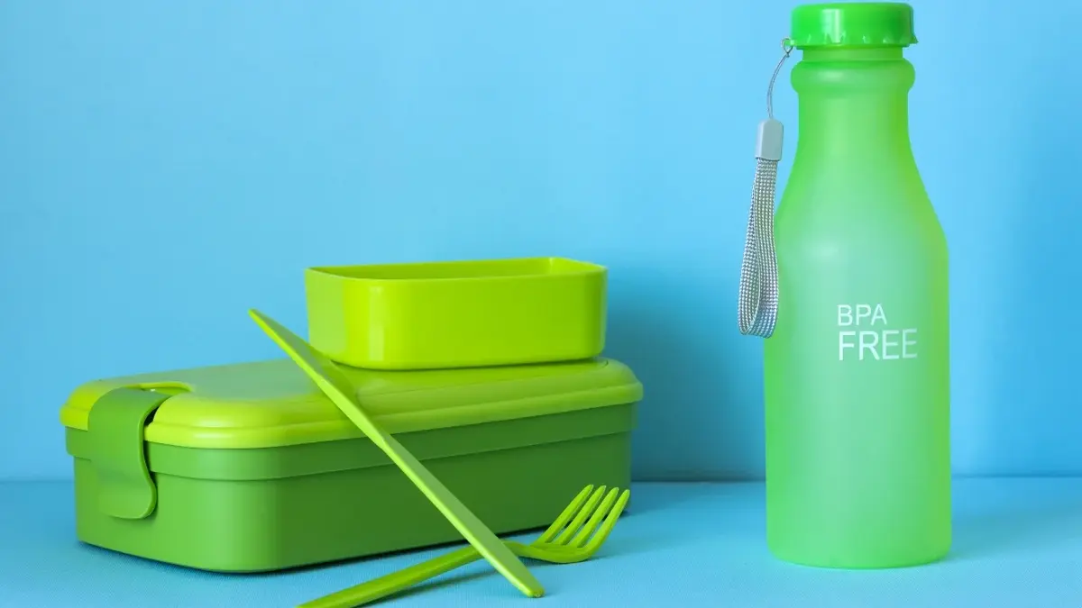 Zielona plastikowa śniadaniówka i butelka na niebieskim tle 