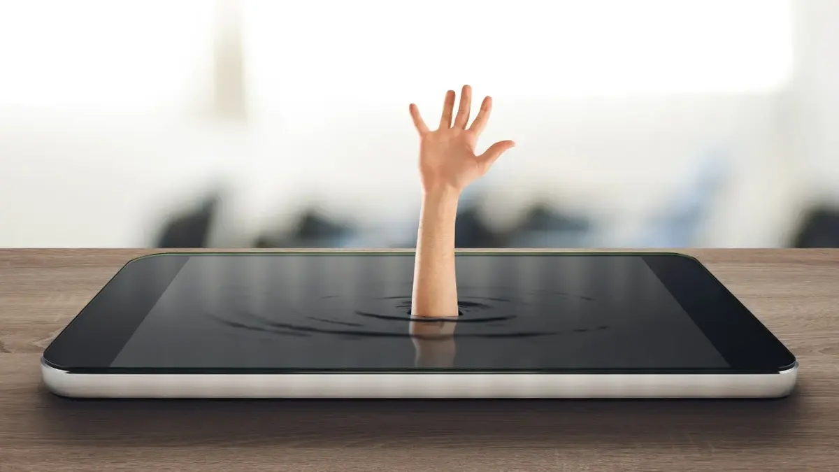 Grafika z ręką wychodząca z leżącego na stole tabletu