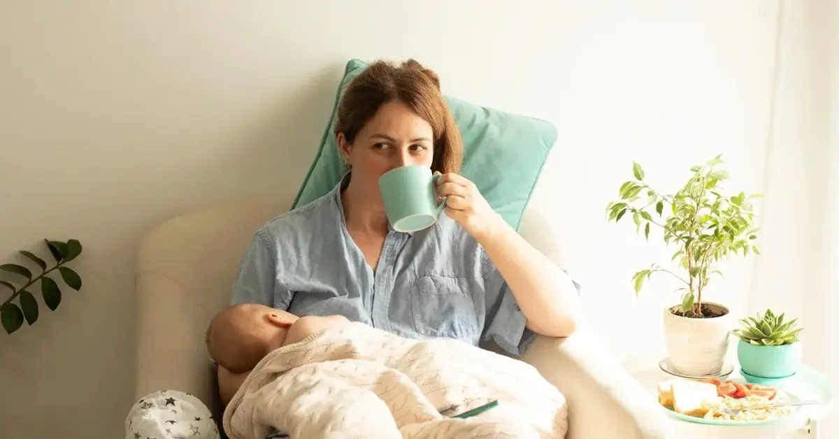 Kobieta karmiąca dziecko piersią i pijąca herbatę z kubka