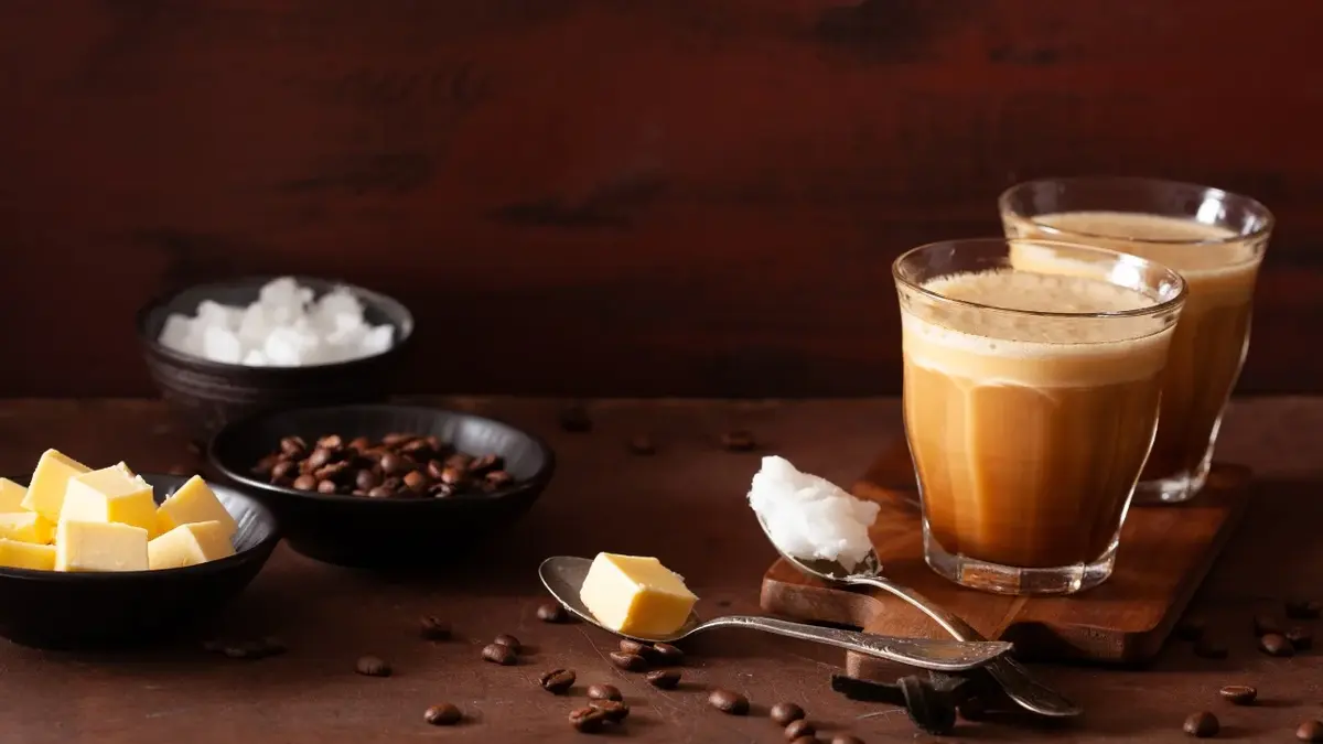 Kawa kuloodporna w szklance, obok masło i olej kokosowy