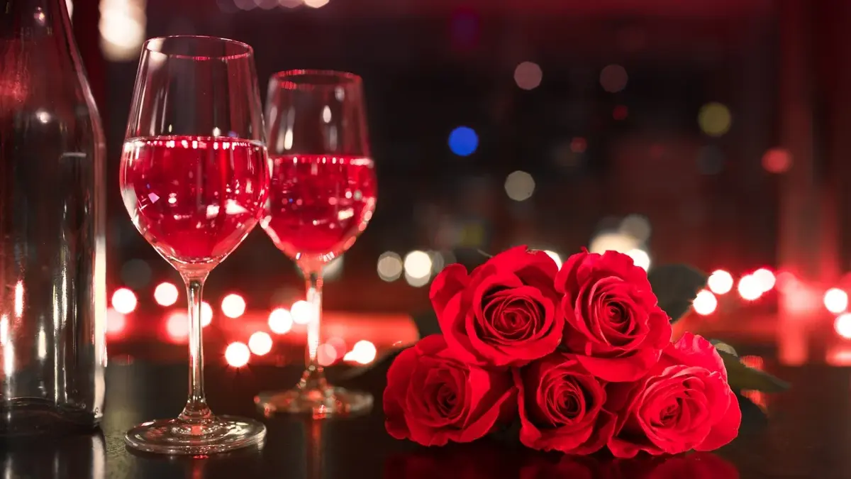 Dwa kieliszki z czerwonym winem i bukiet czerwonych róż