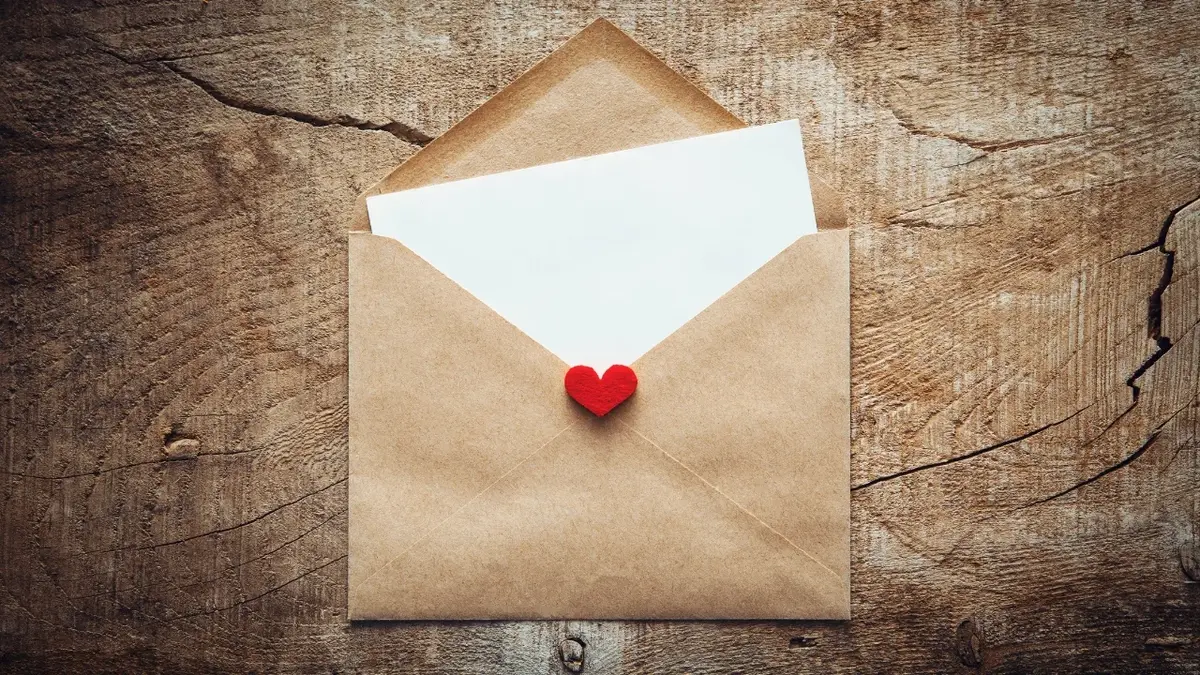 list miłosny w ekologicznej kopercie na drewnianym tle 