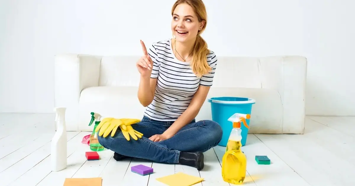 Kobieta siedząca na podłodze z paneli wokół środki czystości