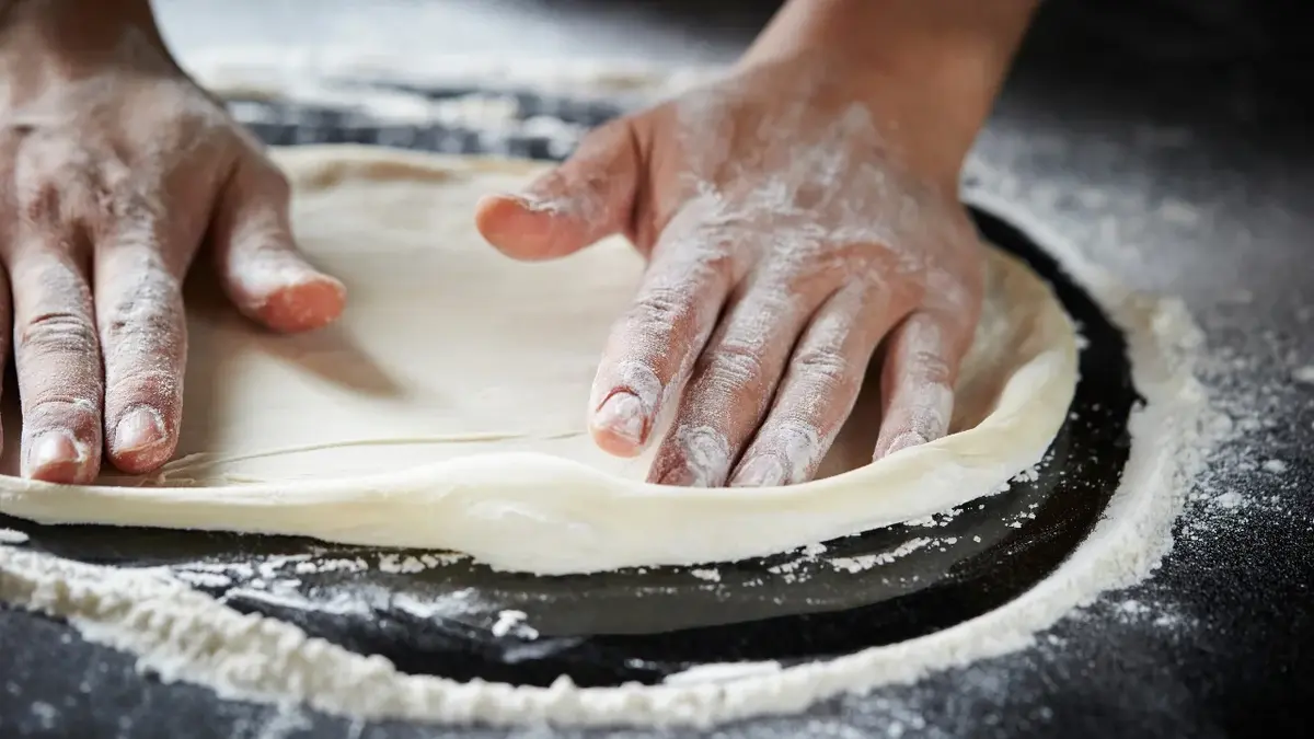 Ciasto na pizze rozwałkowane i układane dwoma rękami 