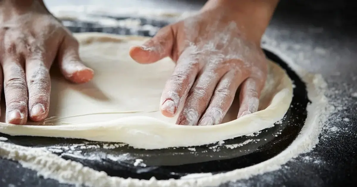 Ciasto na pizze rozwałkowane i układane dwoma rękami 