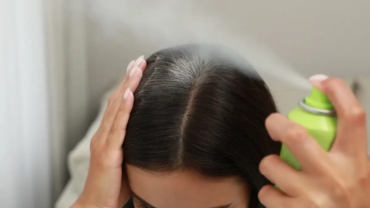 Kobieta nakładająca na włosy suchy szampon