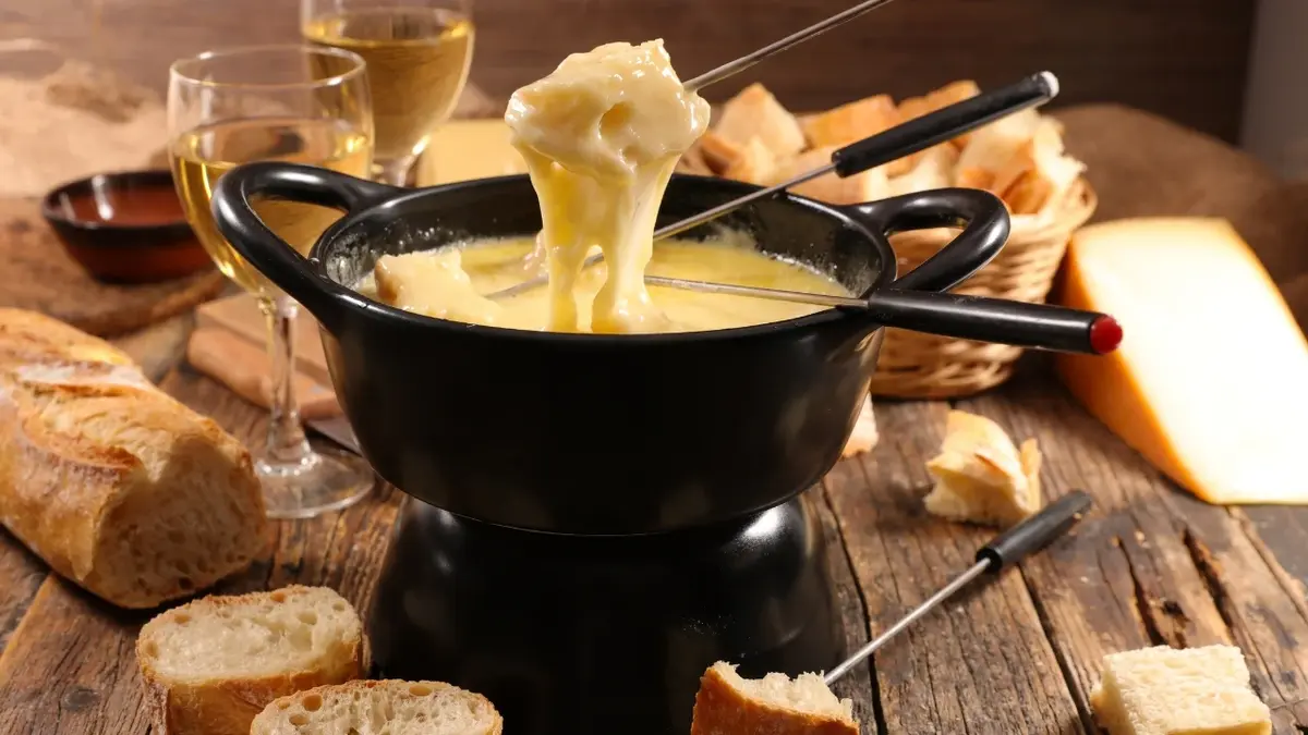 Garnek do fondue serowego. Dookoła bagietka 