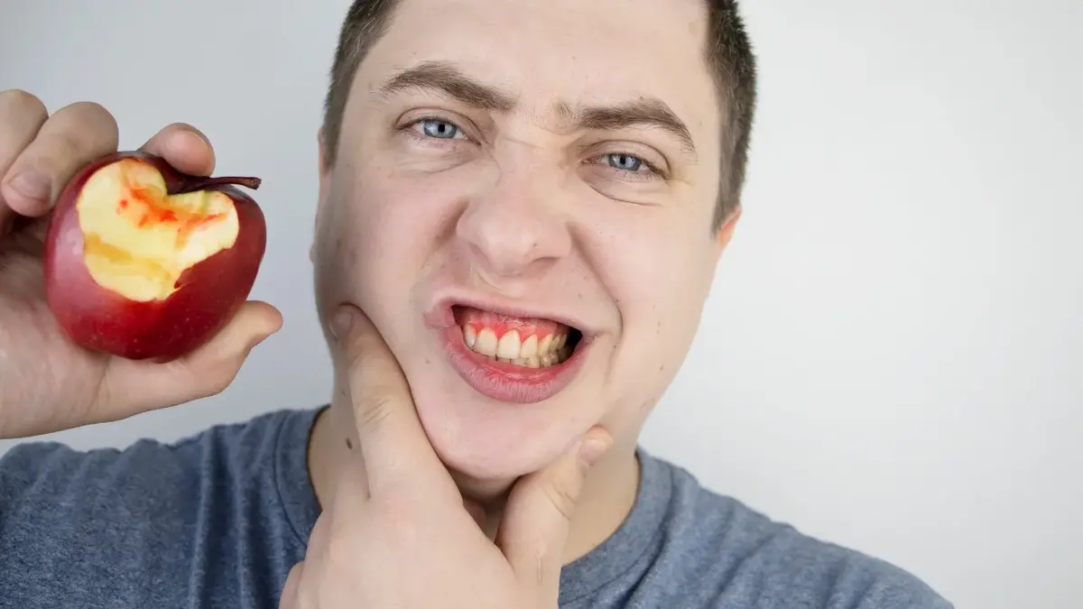Mężczyzna z nadgryzionym jabłkiem w ręce