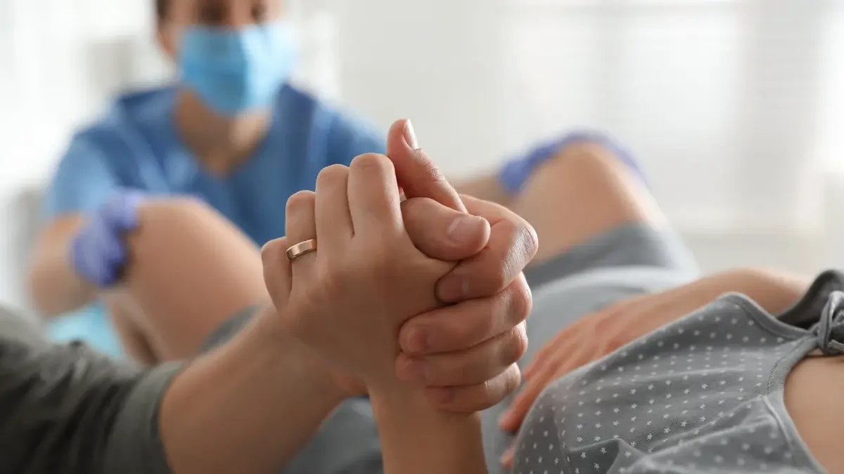 Ręce kobiety i mężczyzny trzymające się podczas porodu 