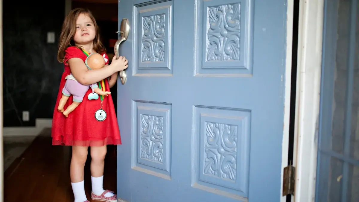 Dziewczynka otwierająca duże niebieskie drzwi do domu