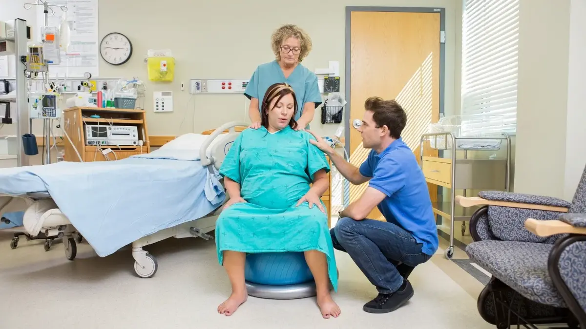 Kobieta podczas podoru na piłce - obok położna i lekarz 