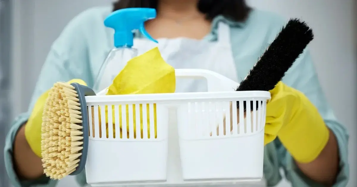 Środki czystości w plastikowym koszyku trzymanym przez kobietę