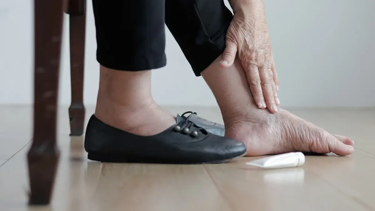 Nogi kobiety smarującej opuchnięta kostke maścią