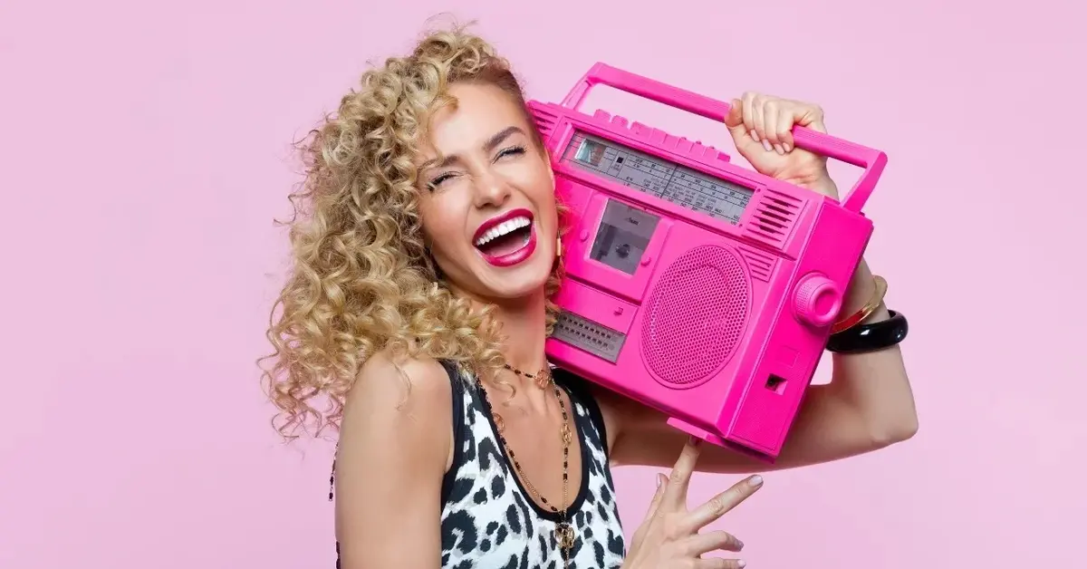 Kobieta z kręconymi włosami trzymająca na ramieniu różowe radio