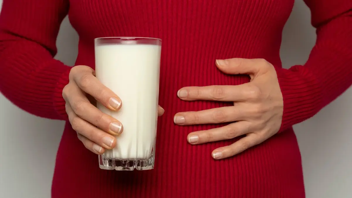 kobeita w bordowym swetrze trzymająca przed soba szklankę mleka