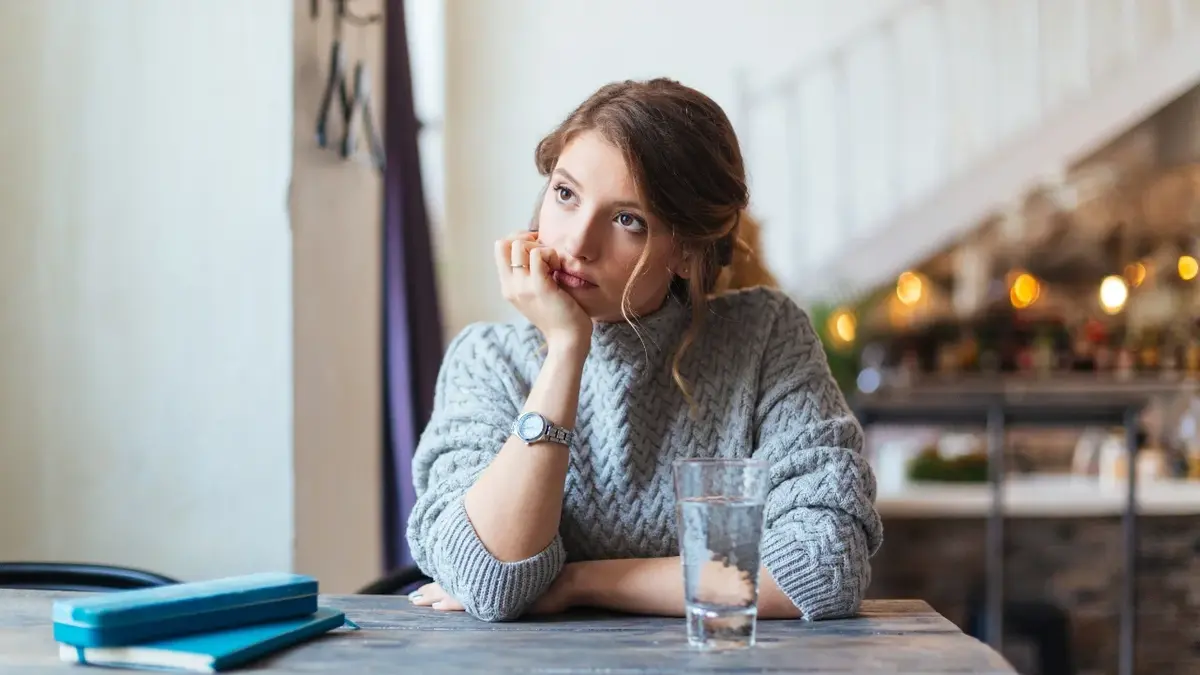 Kobieta siedząca samotnie przy stoliku z głową opartą o rękę