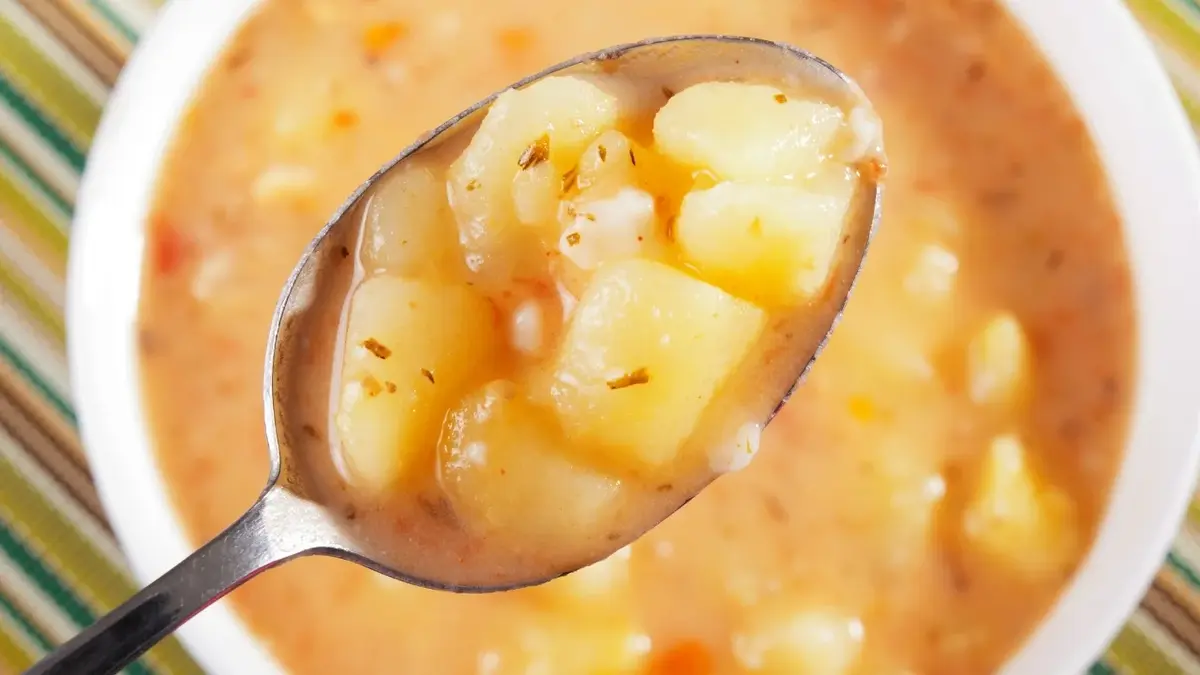 Porcja kartoflanki na łyżce, w tle miseczka z zupą
