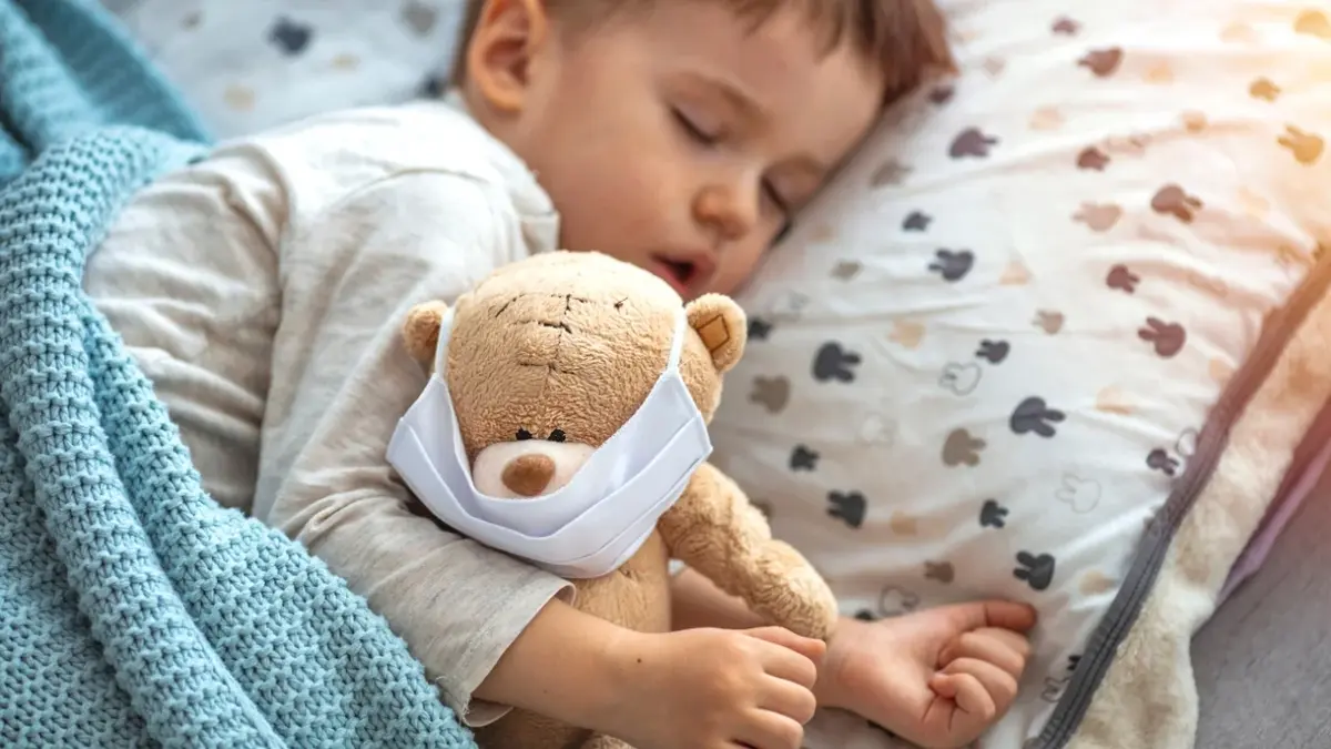 Chore dziecko śpiące w łóżku z misiem przytulanką