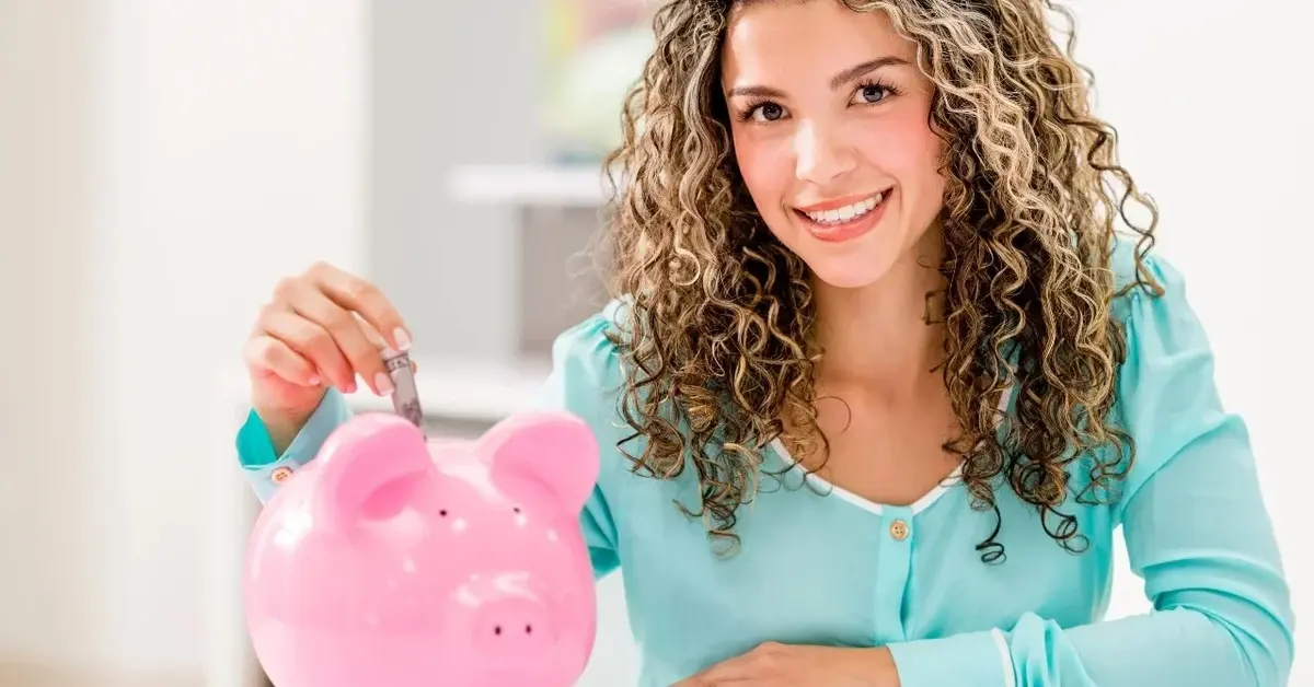 Kobieta wrzucająca pieniądze do różowej świnki skarbonki 