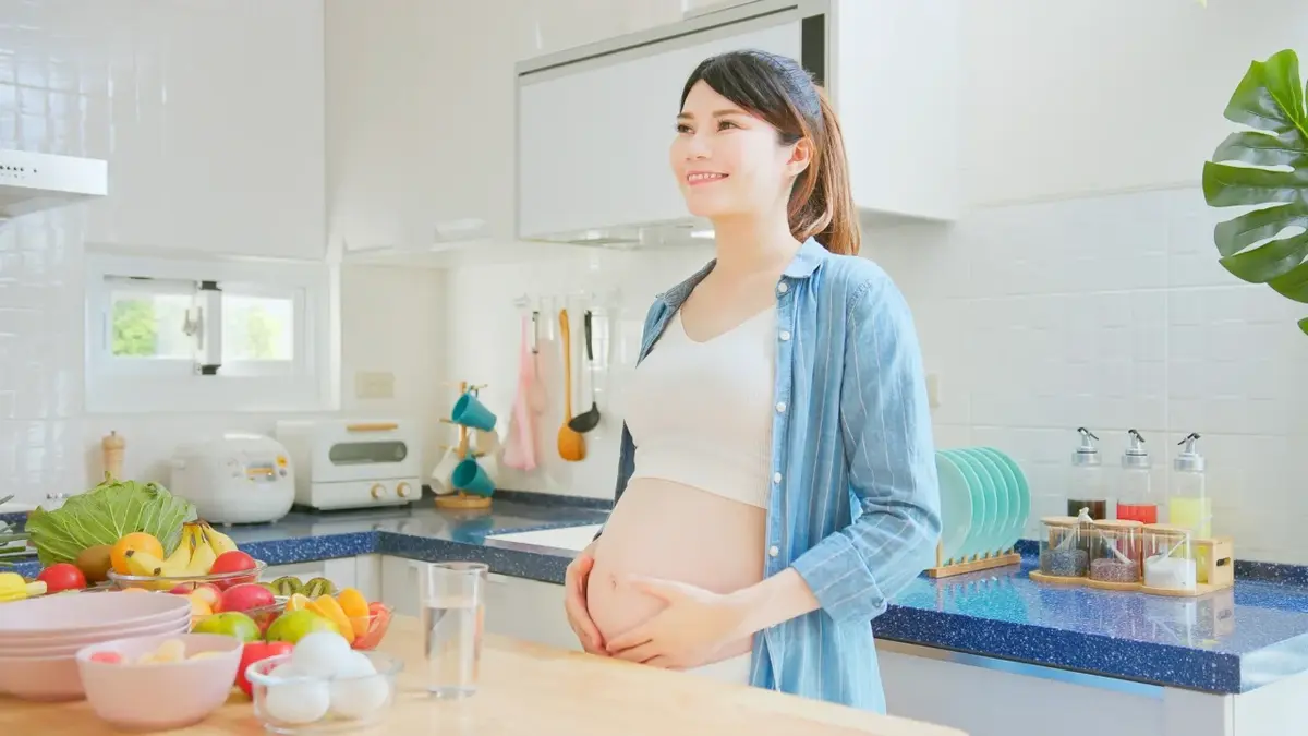 Kobieta w ciąży stojąca przy blacie kuchennym