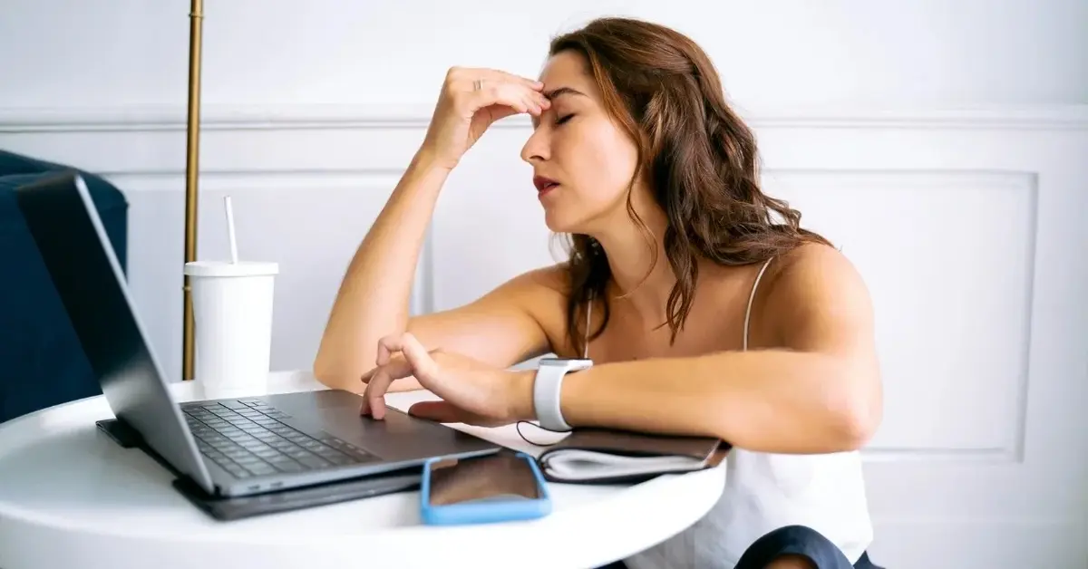 Kobieta siedząca przed komputerem i podpierająca głowę ręką