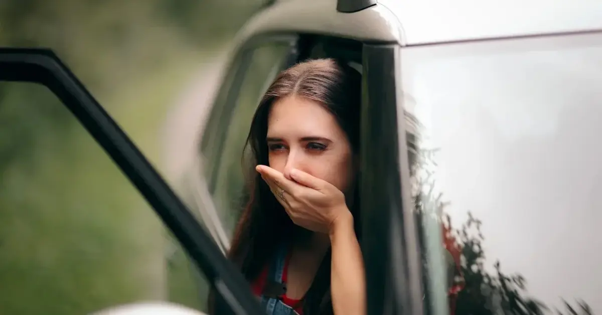 Kobieta w drzwiach samochody zasłaniająca usta