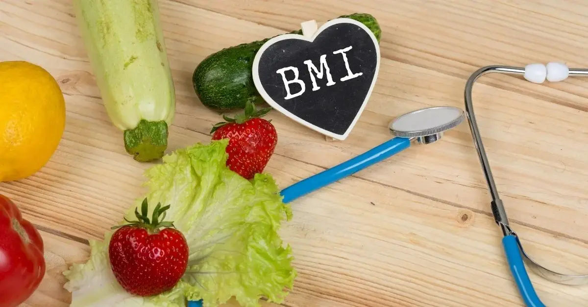 Tabliczka z napisem: "bmi" i stetoskop, obok owoce i warzywa na drewnianym blacie 