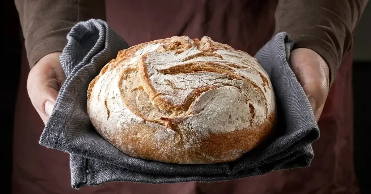 Bochenek chleba trzymany w rękach 