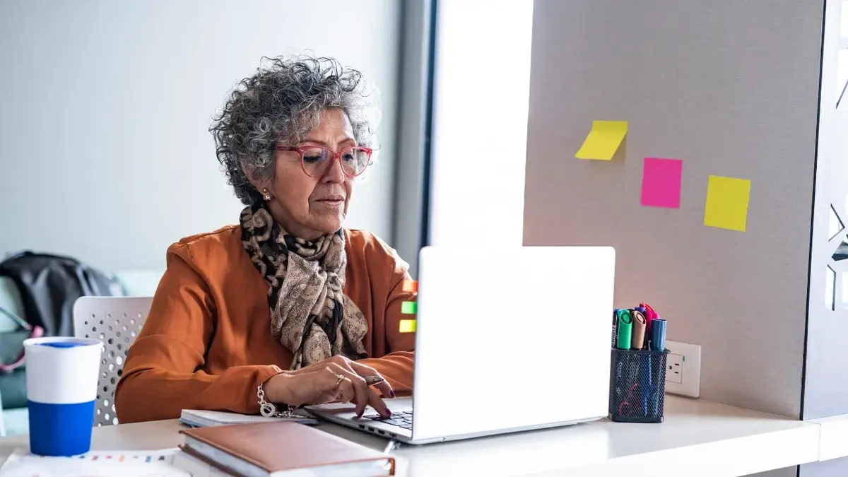 Starsza kobieta siedząca przy biurku przed komputerem