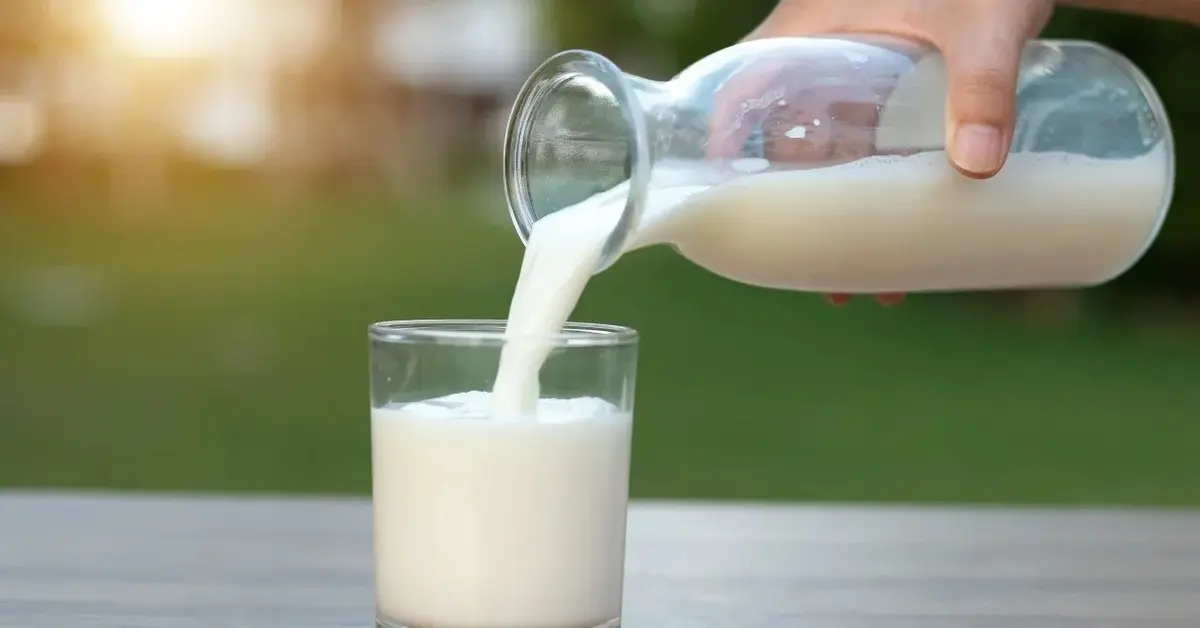 Mleko nalewane do szklanki ze szklanego dzbanka 