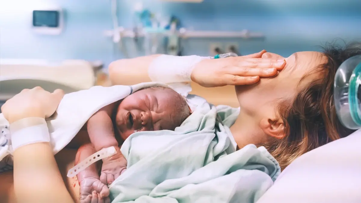 Kobieta zaraz po porodzie z noworodkiem leżącym na jej klatce piersiowej