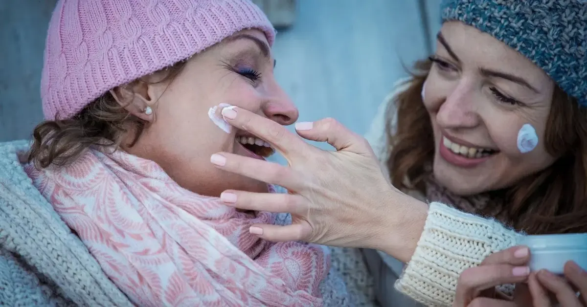 Kobiety w zimowych ubraniach nakładające krem na twarz