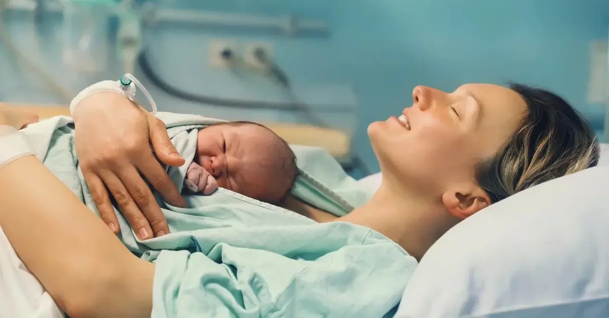 Kobieta zaraz po porodzie z noworodkiem leżącym na jej klatce piersiowej